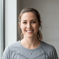 Woman wearing a gray shirt indoors with a neutral background